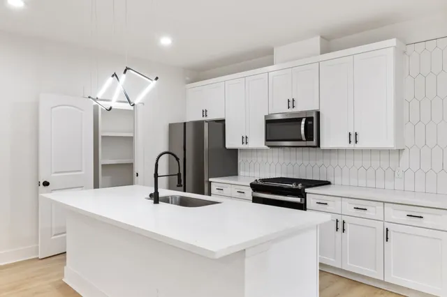 a kitchen with stainless steel appliances a sink a stove a microwave and cabinets