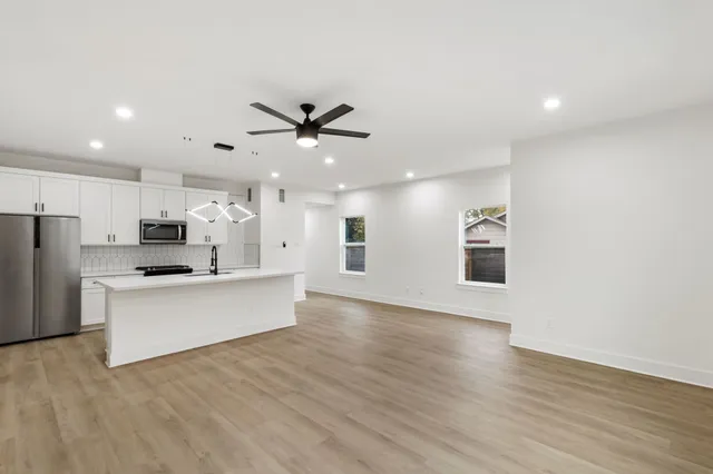 a living room with stainless steel appliances kitchen island a fireplace furniture a refrigerator a sink and a stove