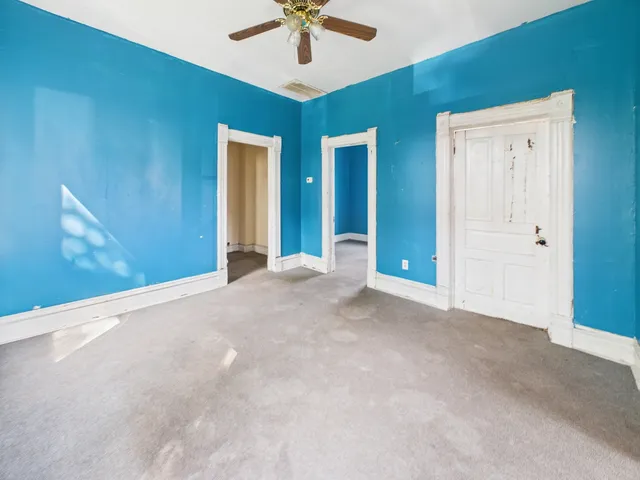 an empty room with windows and fan