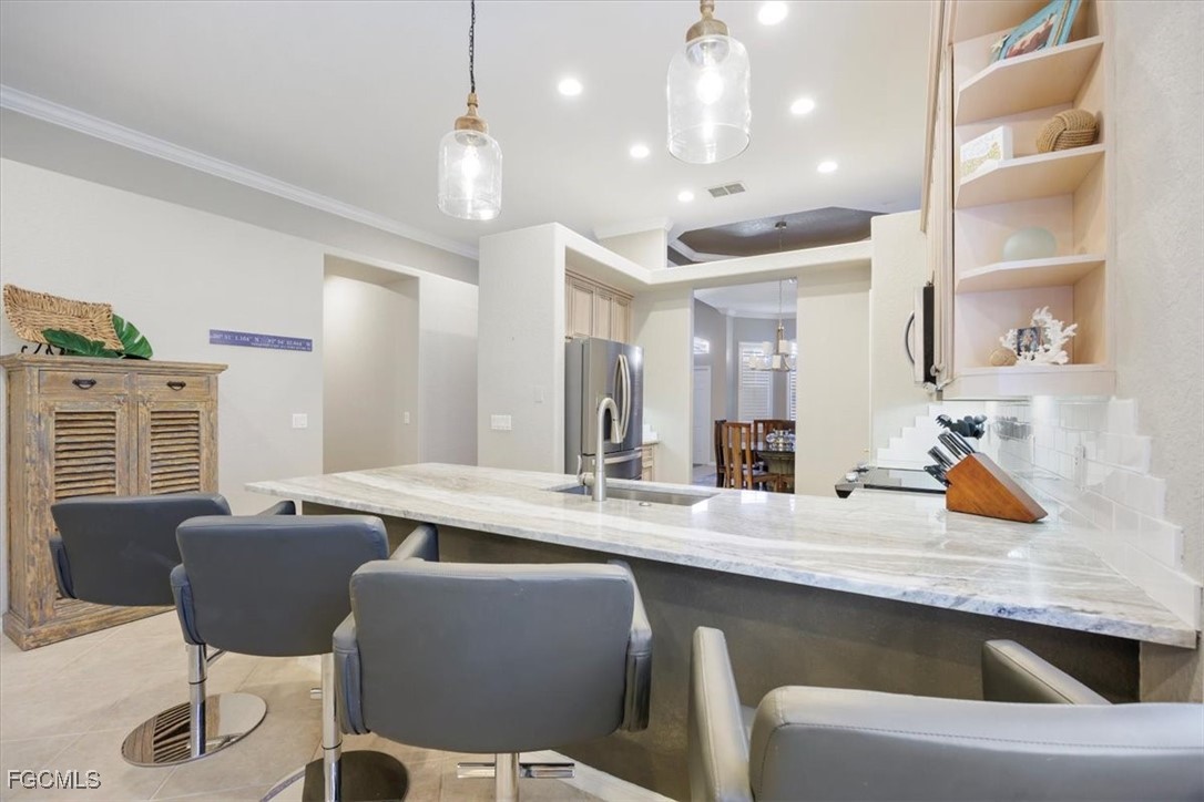 9159 Spring Mountain Way Fort Myers, FL 33908 - Photo 13 of 48 a dining hall with stainless steel appliances kitchen island granite countertop a dining table chairs and a refrigerator