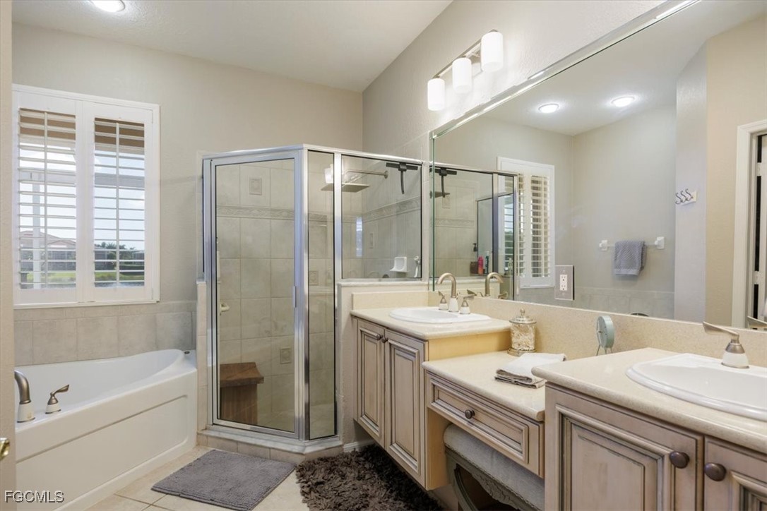 9159 Spring Mountain Way Fort Myers, FL 33908 - Photo 29 of 48 a bathroom with a double vanity sink a large mirror and a bathtub