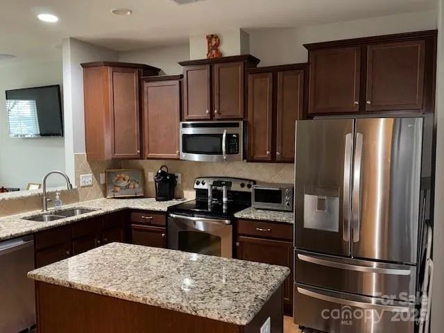 a kitchen with granite countertop a refrigerator stove and sink