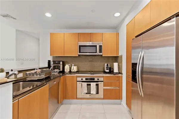 a kitchen with stainless steel appliances granite countertop a stove a sink and a refrigerator