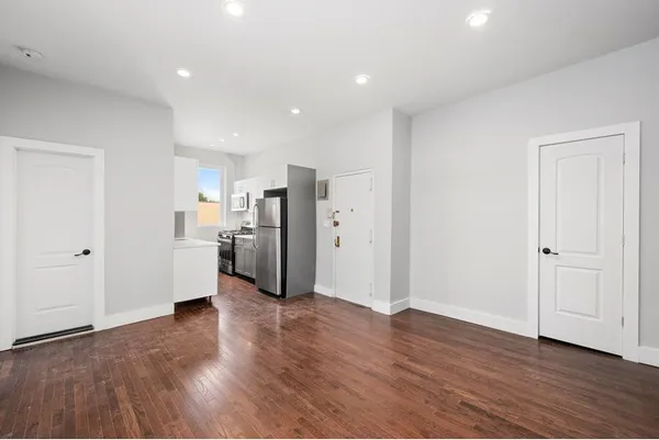 a view of a kitchen with a refrigerator and wooden floor