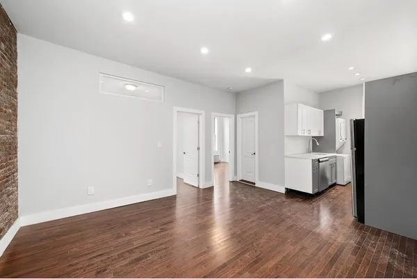 a view of a kitchen with refrigerator and wooden floor