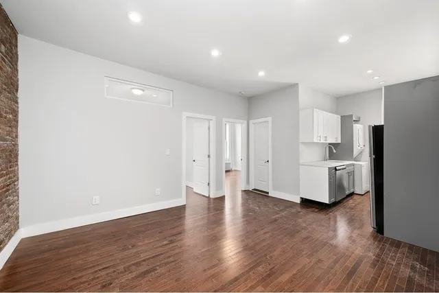 a view of a kitchen with refrigerator and wooden floor