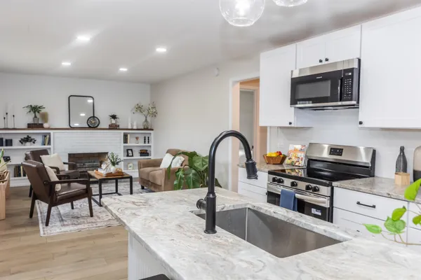 a kitchen with stainless steel appliances granite countertop a stove top oven a sink a dining table and chairs with wooden floor