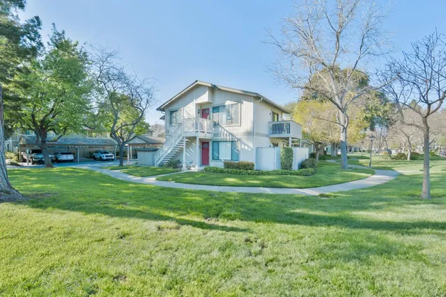 a view of a house with a big yard and large trees