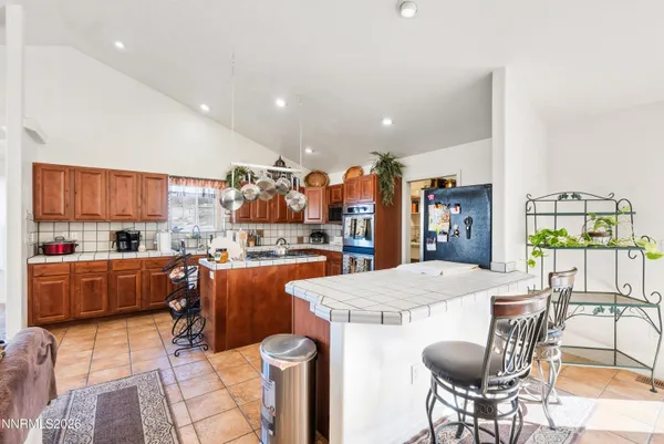 a living room with stainless steel appliances furniture a dining table and kitchen view