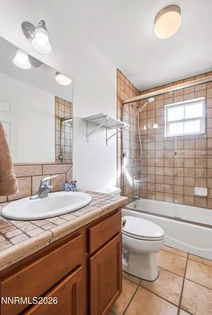 a bathroom with a granite countertop toilet sink and mirror