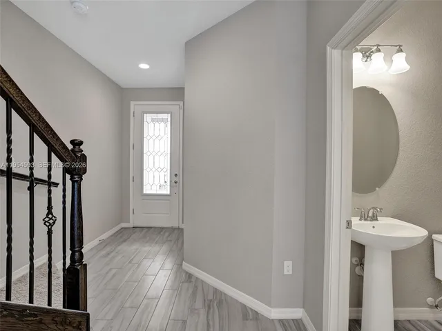a view of a hallway with wooden floor and a mirror