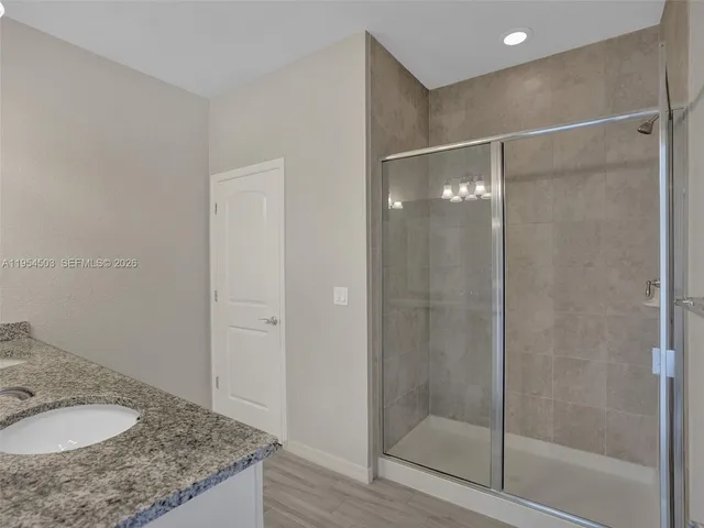 a bathroom with a granite countertop shower and a sink