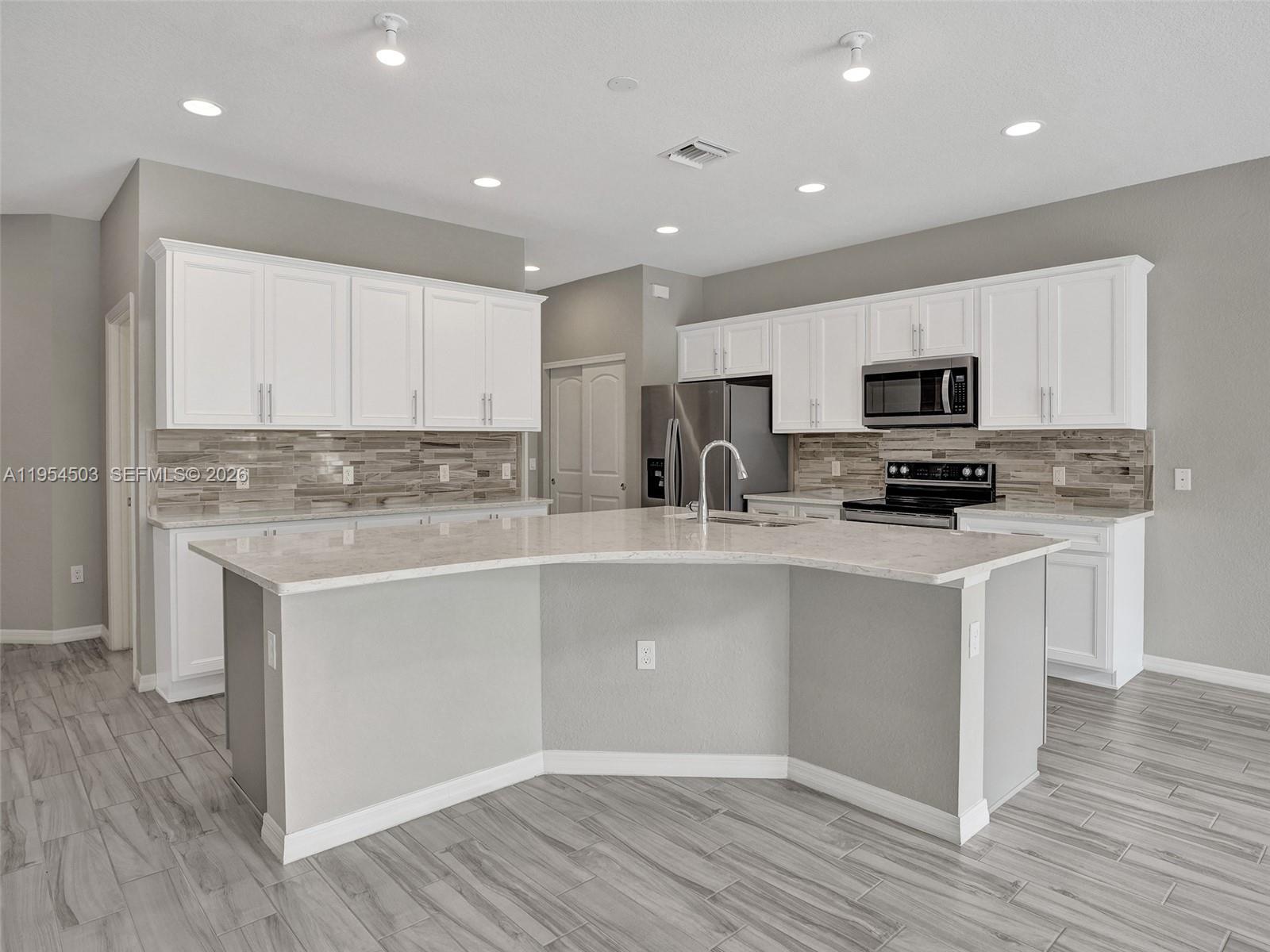 8330 Rearing Lane Lake Worth, FL 33467 - Photo 4 of 39 a kitchen with stainless steel appliances granite countertop a stove top oven a sink a refrigerator and white cabinets with wooden floor