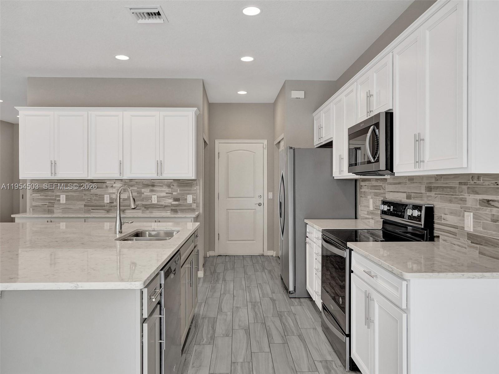 8330 Rearing Lane Lake Worth, FL 33467 - Photo 6 of 39 a kitchen with stainless steel appliances a stove sink microwave and cabinets