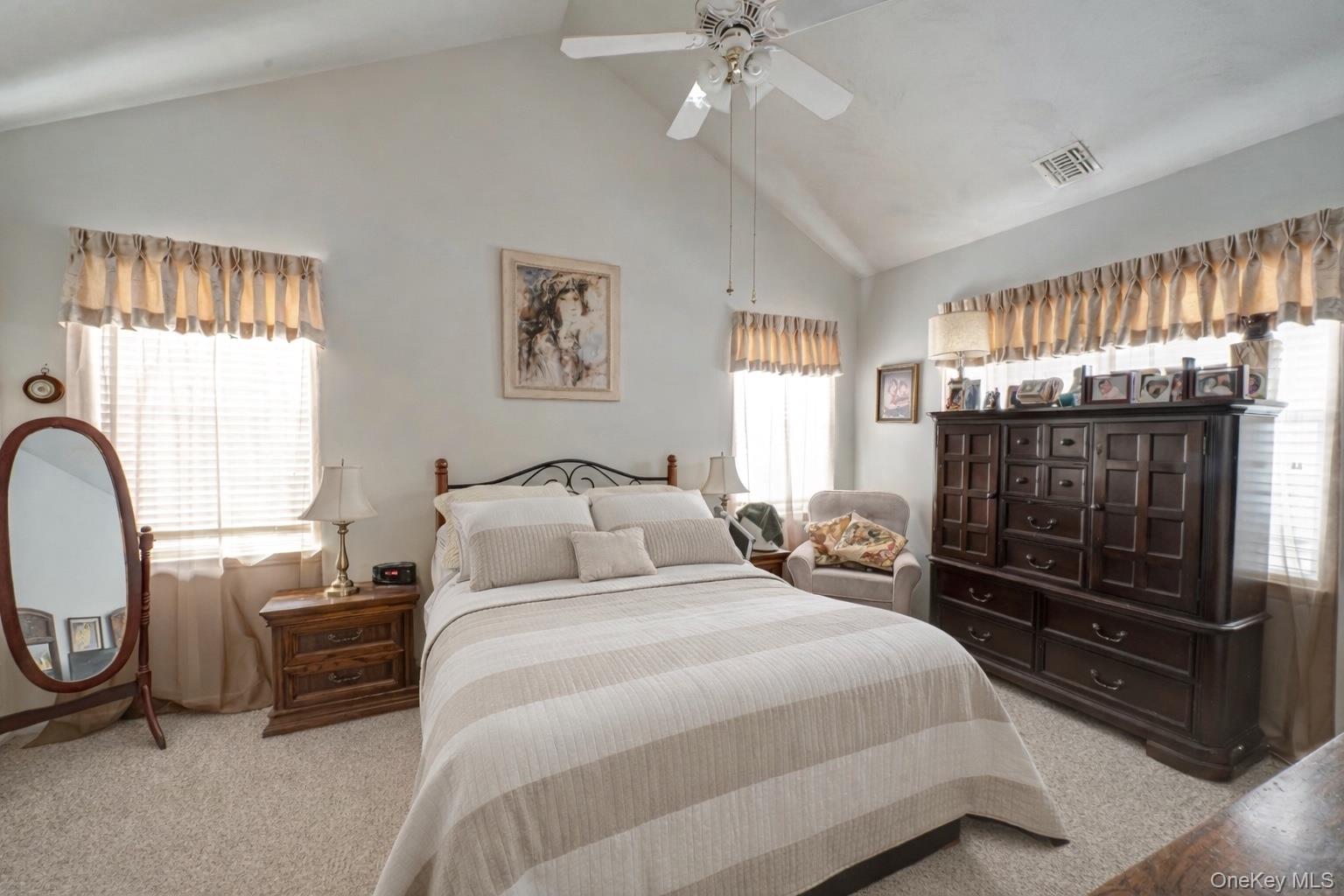 408 Leisure Drive Ridge, NY 11961 - Photo 11 of 17 a bedroom with a bed a mirror on the dresser and chandelier