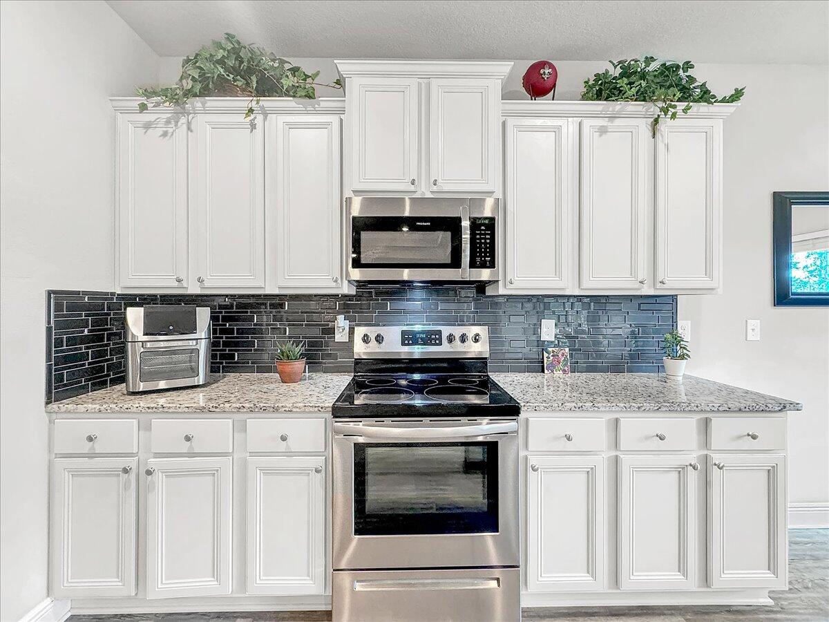 3568 Moonstone Drive Navarre, FL 32566 - Photo 8 of 39 a kitchen with granite countertop white cabinets and stainless steel appliances