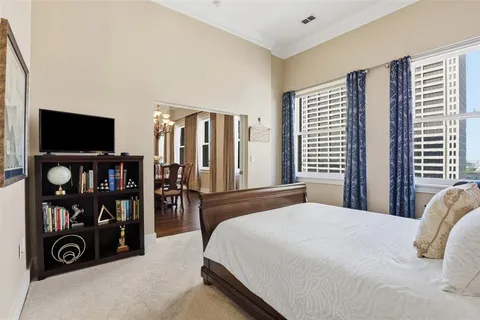 a bedroom with a bed a flat screen tv and a large window
