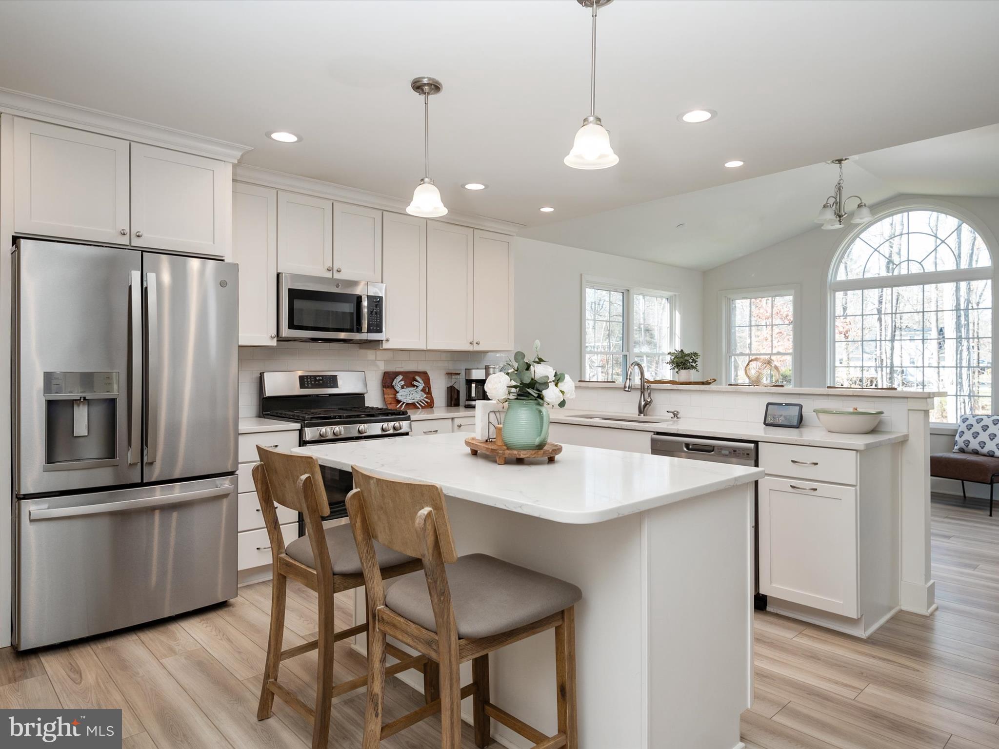8412 Maryland Road Pasadena, MD 21122 - Photo 17 of 61 a kitchen with stainless steel appliances granite countertop a stove a sink a refrigerator a microwave oven with a dining table and chairs