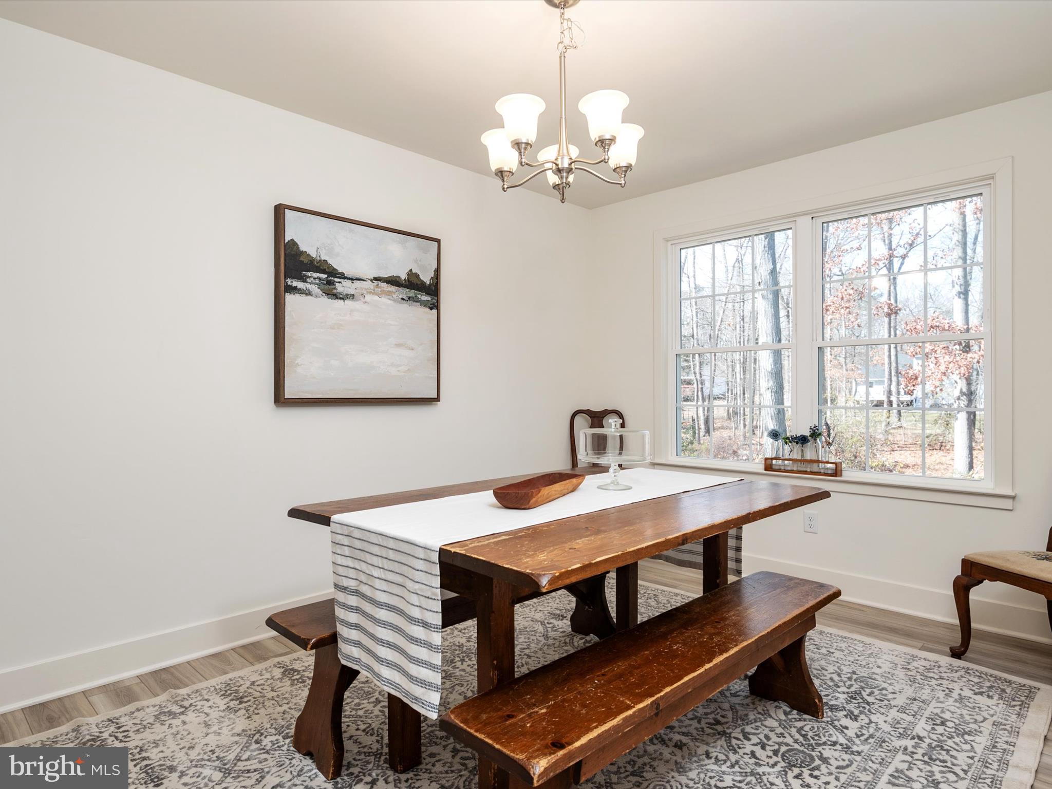 8412 Maryland Road Pasadena, MD 21122 - Photo 25 of 61 a dining room with wooden floor a chandelier a wooden table and chairs