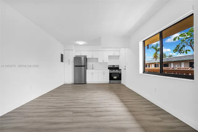 a view of a kitchen with wooden floor electronic appliances and windows