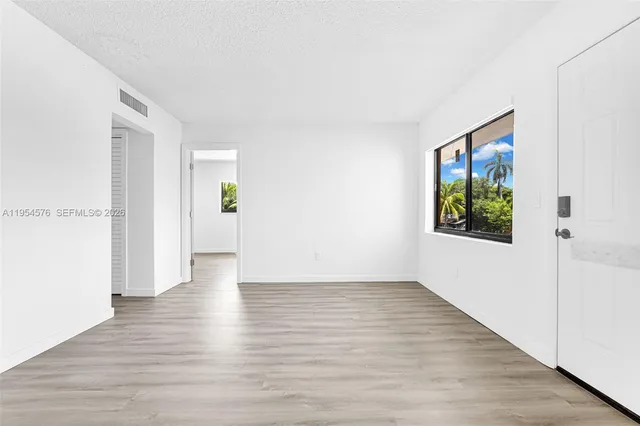 an empty room with wooden floor mirror and windows
