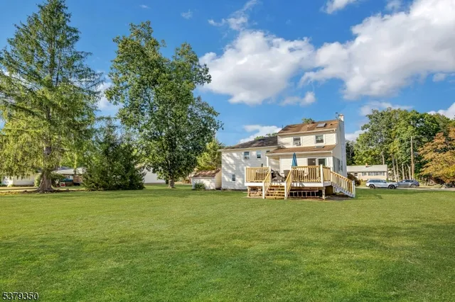 a view of a house with a big yard and large trees