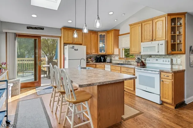 a kitchen with stainless steel appliances granite countertop a stove a refrigerator a sink dishwasher a dining table and chairs with wooden floor
