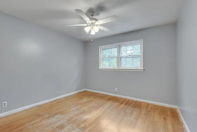 an empty room with a chandelier fan and windows