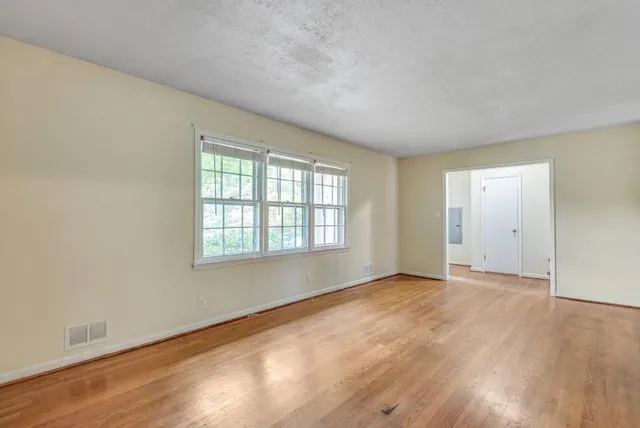 an empty room with wooden floor and windows