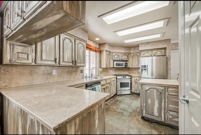 a kitchen with stainless steel appliances granite countertop a sink window and cabinets