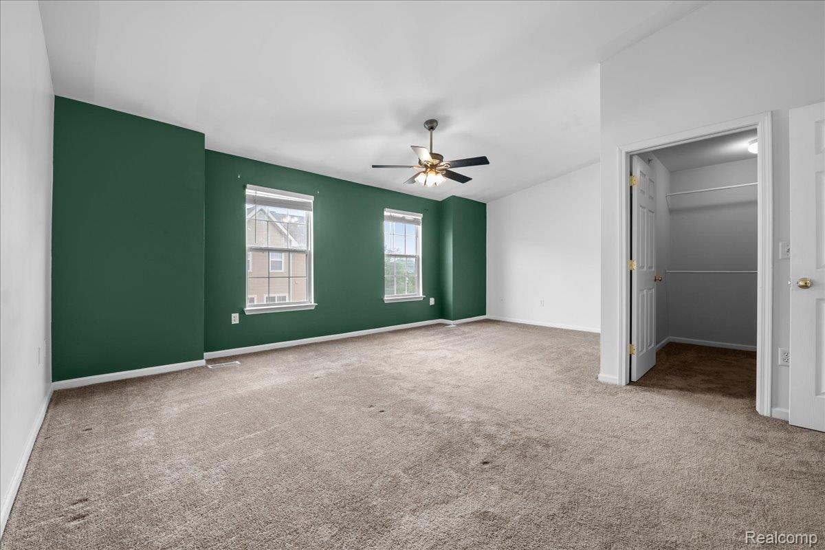 22684 Goddard Road Taylor, MI 48180 - Photo 21 of 29 Spacious room featuring a deep green accent wall, two windows with white trim, and light brown carpeting