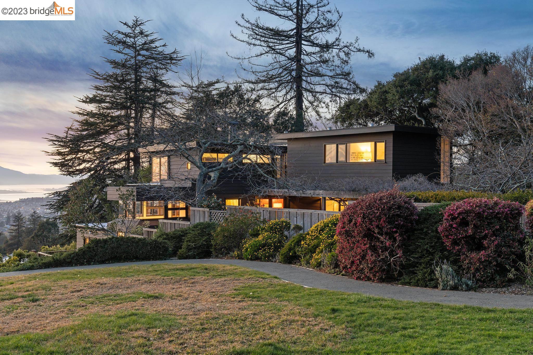 a front view of a house with a yard and a large tree