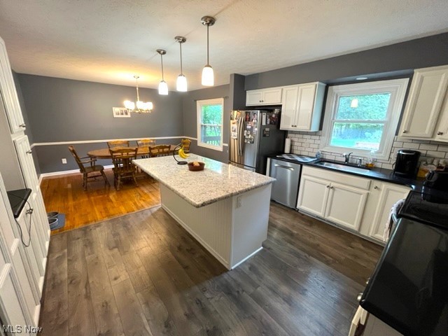 934 Andrews Road Medina, OH 44256 - Photo 10 of 27 Kitchen with decorative light fixtures, backsplash, white cabinetry, appliances with stainless steel finishes, plenty of natural light, dark hardwood flooring, and a kitchen island with sink