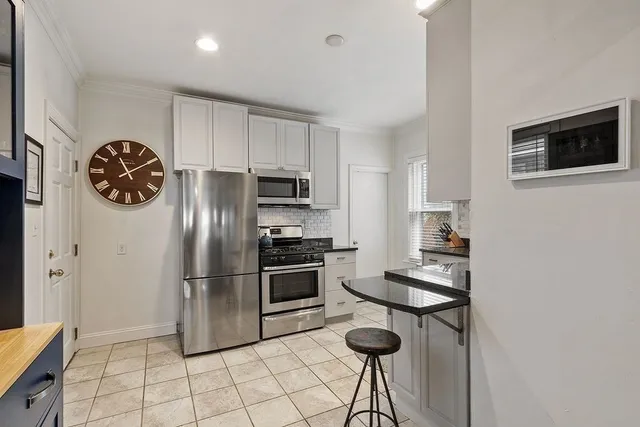 a kitchen with granite countertop a refrigerator a stove a microwave and island