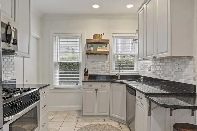 a kitchen with granite countertop a sink stove and cabinets