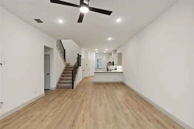 an empty room with wooden floor a ceiling fan and windows