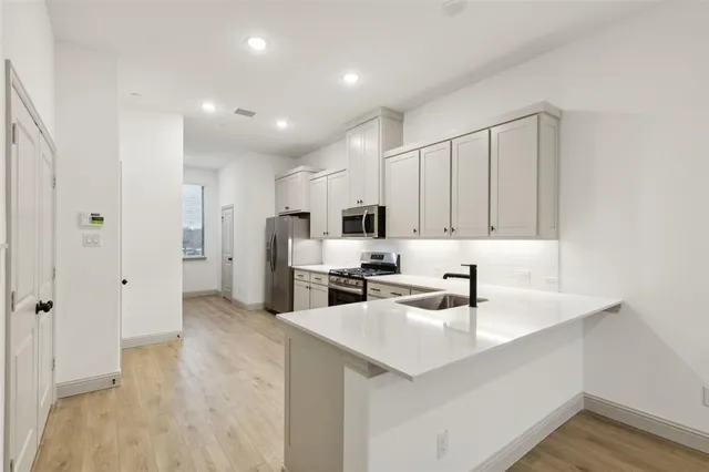 a large white kitchen with kitchen island a sink stainless steel appliances and cabinets