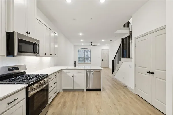 a large white kitchen with kitchen island a sink stainless steel appliances and cabinets