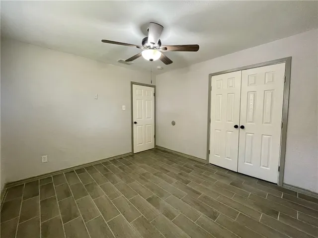 an empty room with closet and a chandelier fan