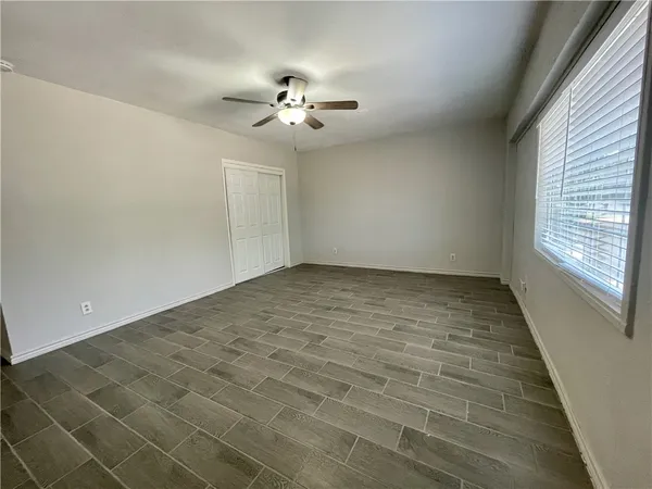 an empty room with windows and fan