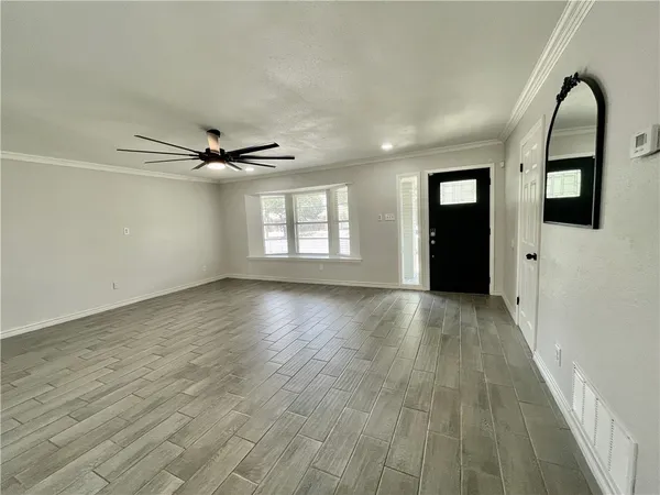 a view of empty room with wooden floor and window