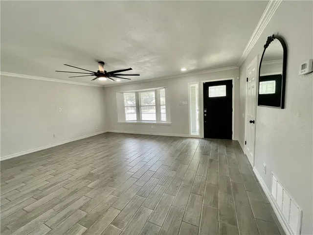 a view of empty room with wooden floor and window