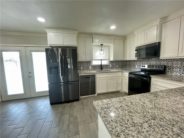 a kitchen with stainless steel appliances granite countertop a refrigerator stove a sink and a microwave