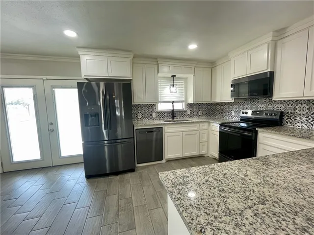 a kitchen with stainless steel appliances granite countertop a refrigerator stove a sink and a microwave