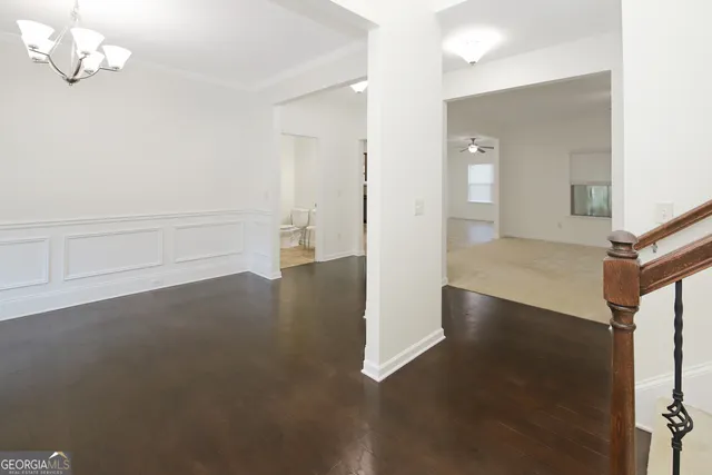 an empty room with wooden floor chandelier and windows