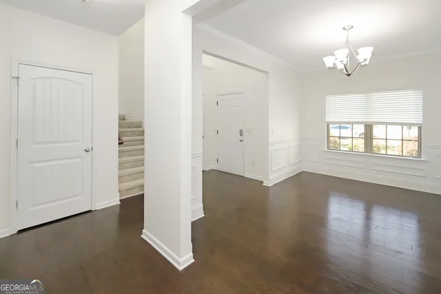 an empty room with chandelier fan and windows
