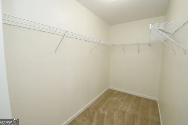 an empty room with chandelier fan and windows