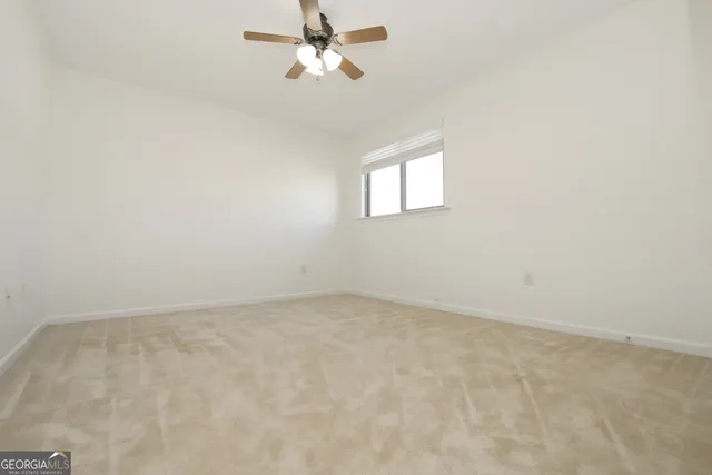 an empty room with wooden floor and windows with curtains