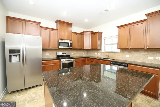 a kitchen with stainless steel appliances granite countertop a refrigerator a stove a sink and a counter space