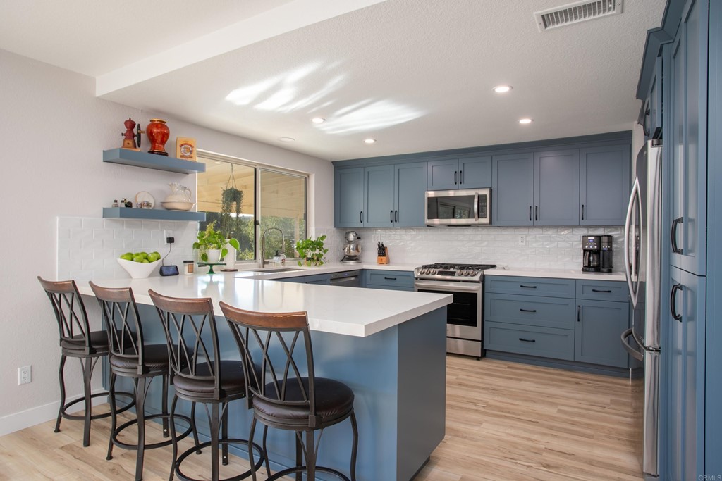 25929 Matlin Road Ramona, CA 92065 - Photo 4 of 19 a kitchen with stainless steel appliances kitchen island granite countertop a stove a refrigerator a microwave oven with a dining table and chairs